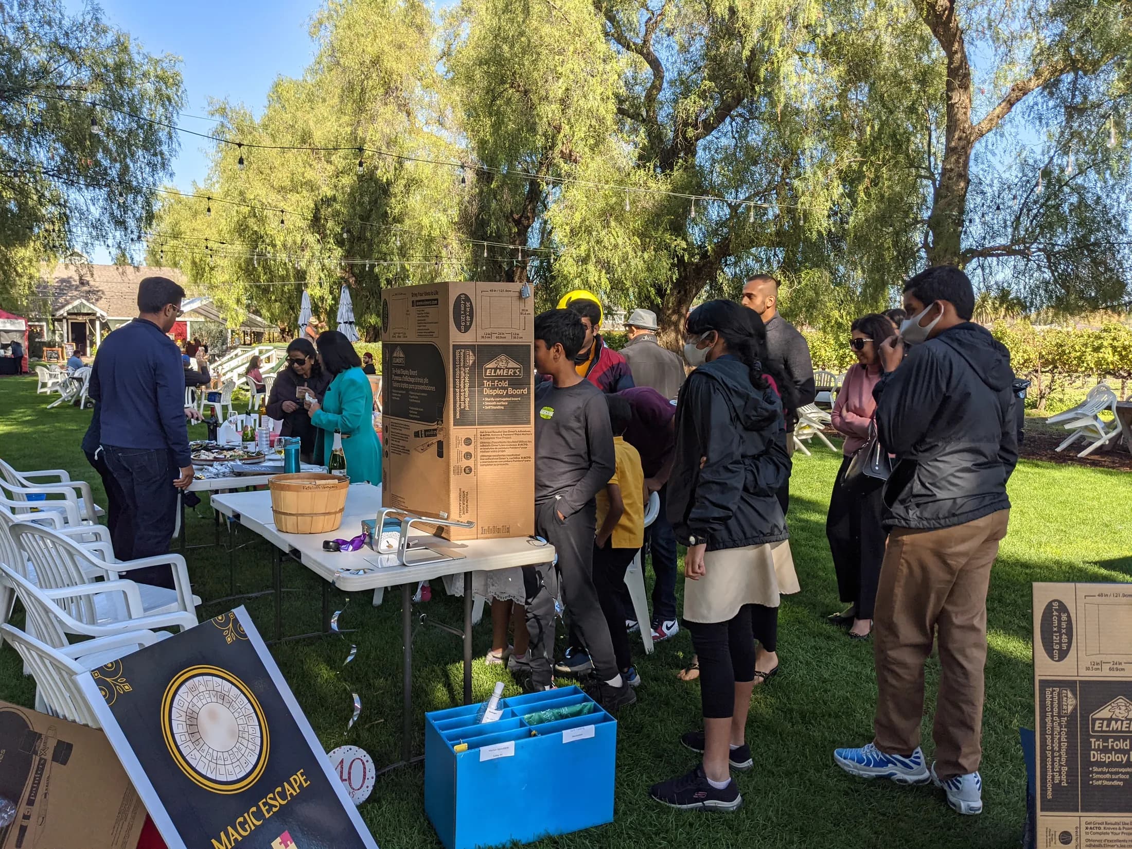 An outdoor fundraiser table with the Magic Escape sign in the foreground